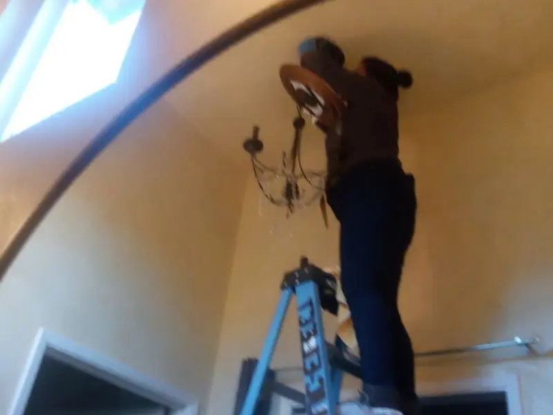 Electrician installing a chandelier in a McCandless residence
